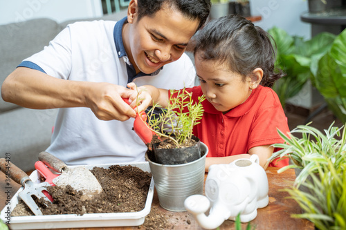 father and his daughters are planting potted plants while at home