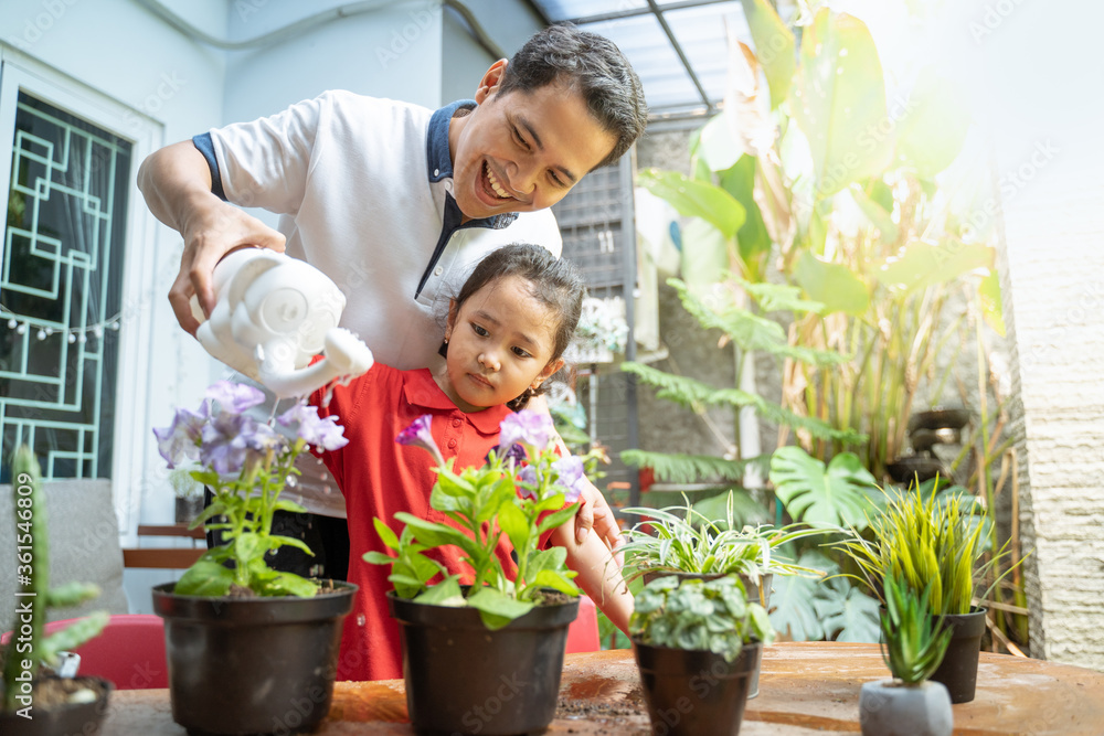 Asian father and daughter using watering can to watering potted plants to fill activities at home Asian father and daughter using watering can to watering potted plants to fill activities at home