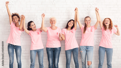 Breast Cancer Support Group Holding Raised Hands Over White Wall