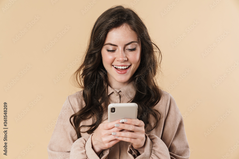 Image of cheerful cute woman smiling and typing on mobile phone Image of cheerful cute woman smiling and typing on mobile phone