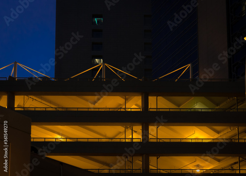 Multistorey car park illuminated at night with a building on the background