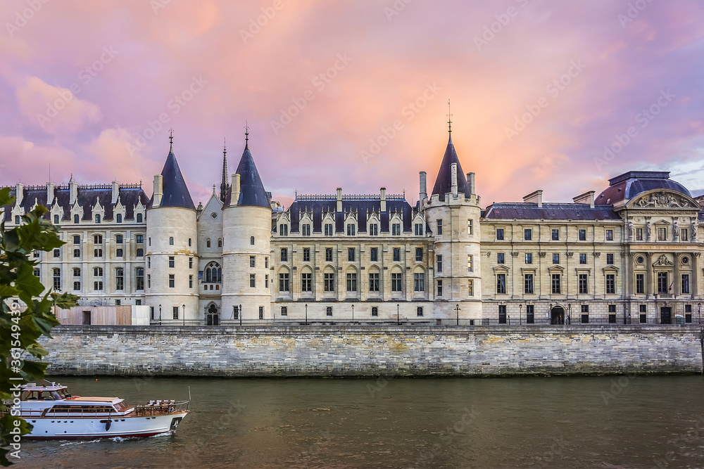 Fototapeta premium Castle Conciergerie - former royal palace and prison. Conciergerie located on the west of the Cite Island and today it is part of larger complex known as Palais de Justice. Paris, France. Sunset.