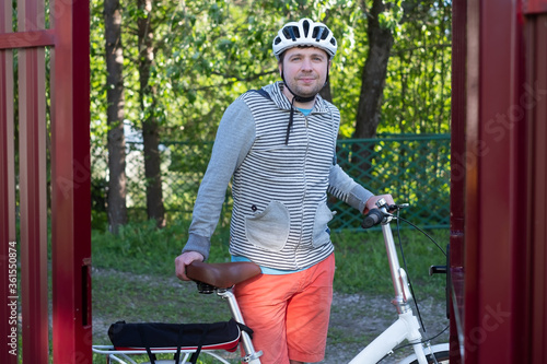 Young cauacasian man in helmet cycling outdoor near fence photo