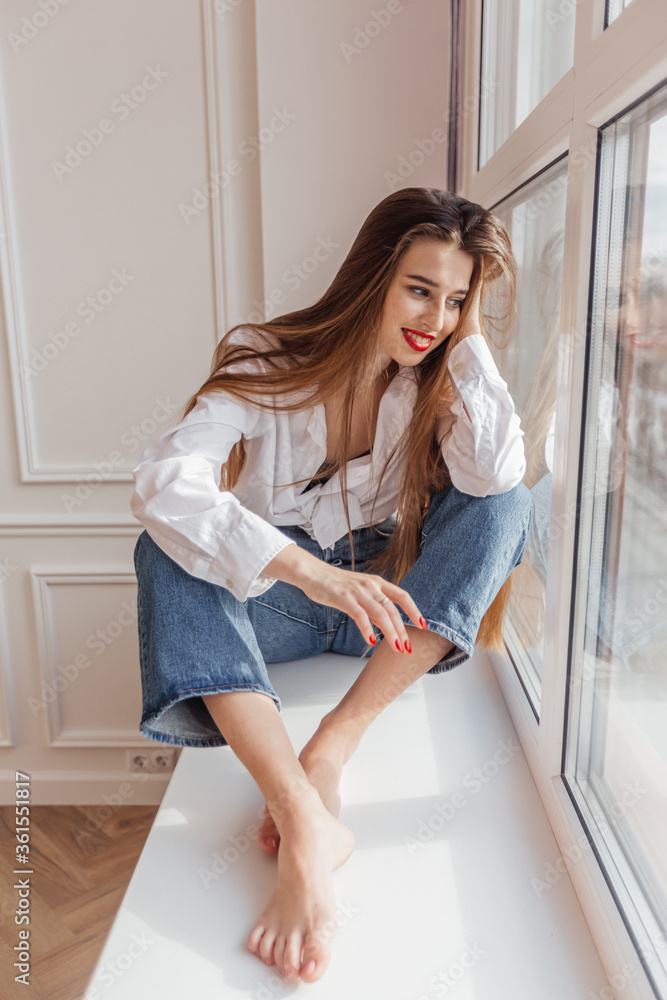 beautiful girl sitting on the window and smiling beautiful girl sitting on the window and smiling