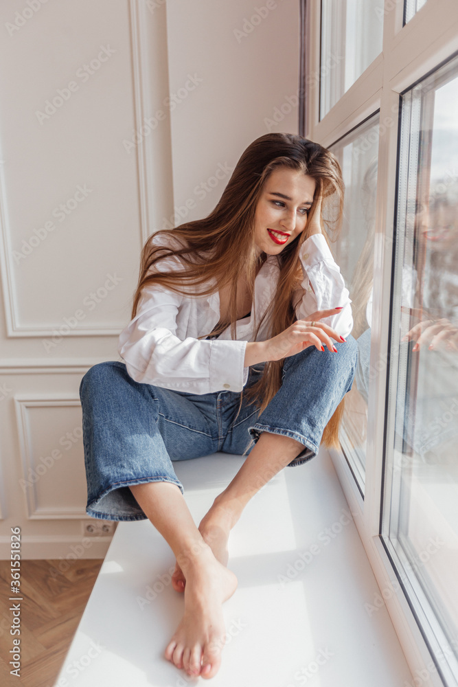 beautiful girl sitting on the window and smiling beautiful girl sitting on the window and smiling