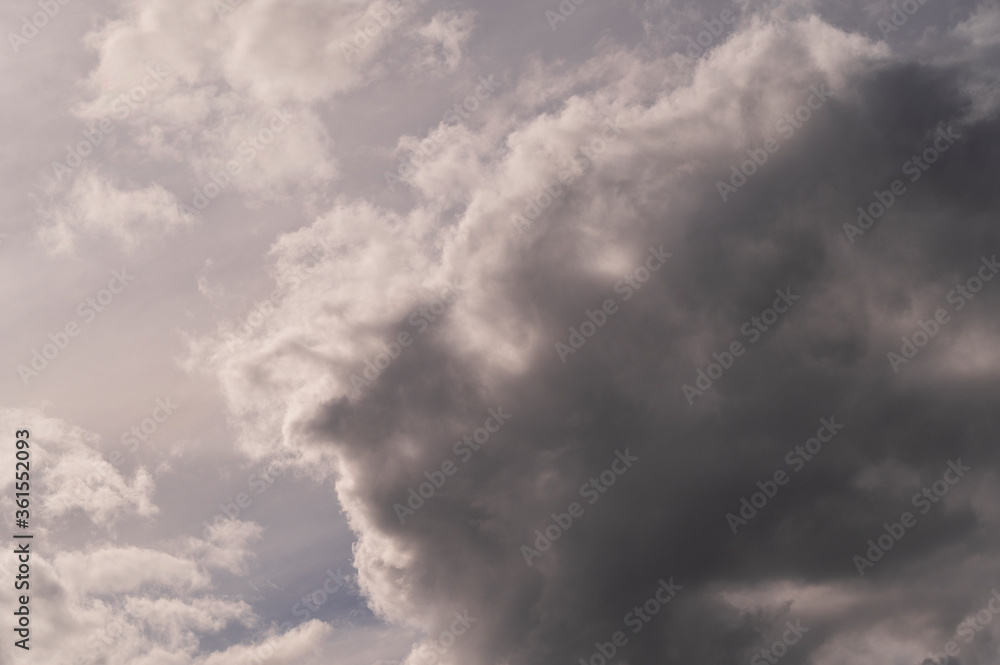 background of gray atmospheric clouds and clouds in the shape of a human face looking at the sunlight