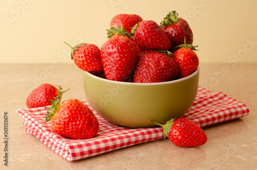 Fresh red strawberries in a bowl on wood table  background and towel