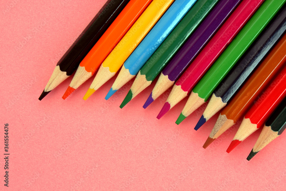 Colored pencils on a pink background. Lots of different colored pencils. Colorful pencil. Pencils are sharp. Pencils lie diagonally in upper right corner. Close-up. Copy space. Background. Flat lay. Colored pencils on a pink background. Lots of different colored pencils. Colorful pencil. Pencils are sharp. Pencils lie diagonally in upper right corner. Close-up. Copy space. Background. Flat lay.