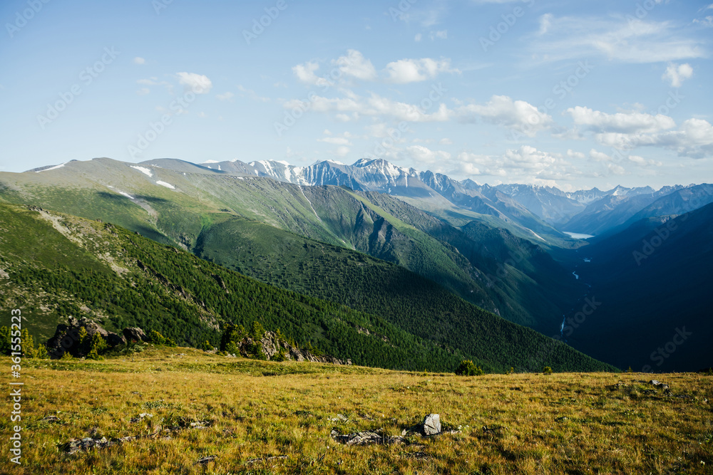 Fototapeta premium Awesome vivid view to great mountains, glacier and green forest valley with alpine lake and river. Beautiful alpine landscape of vast expanses. Wonderful colorful highland scenery with giant mountains