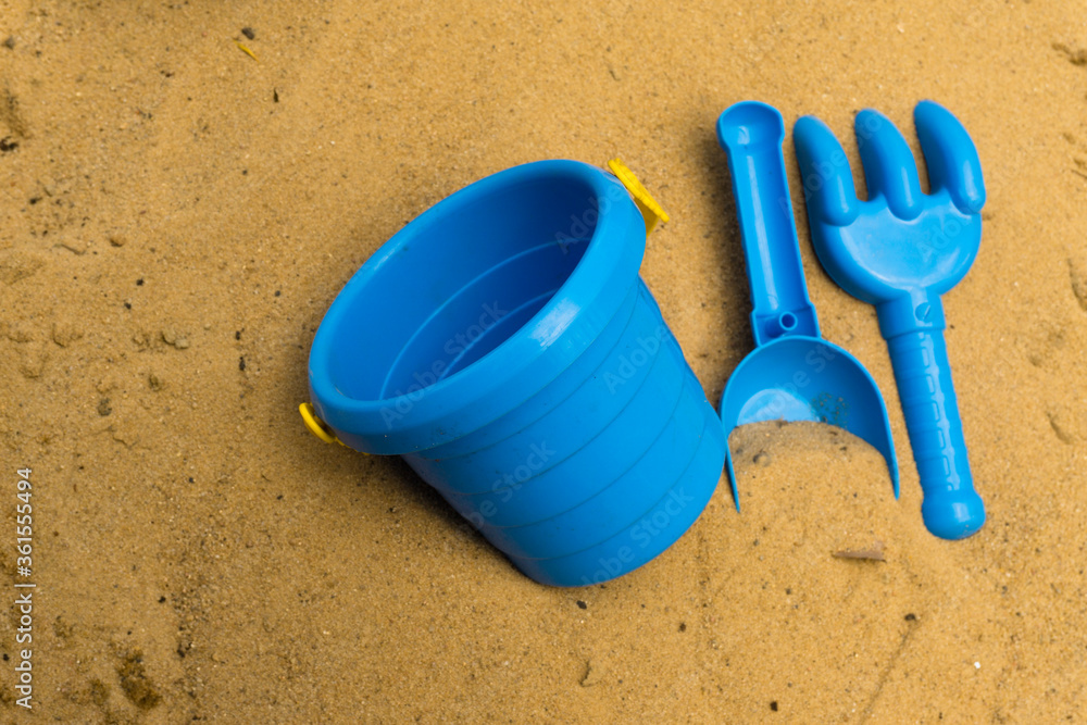 Children's games during quarantine in the sandbox. A medical mask, a shovel, a rake and a bucket for games on the street to lock down. Children's games during quarantine in the sandbox. A medical mask, a shovel, a rake and a bucket for games on the street to lock down.