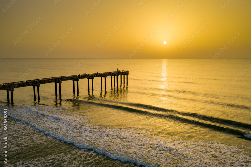 A hazy sunrise from Saharan dust in the atmosphere at the Saint Augustine Beach pier in Florida.