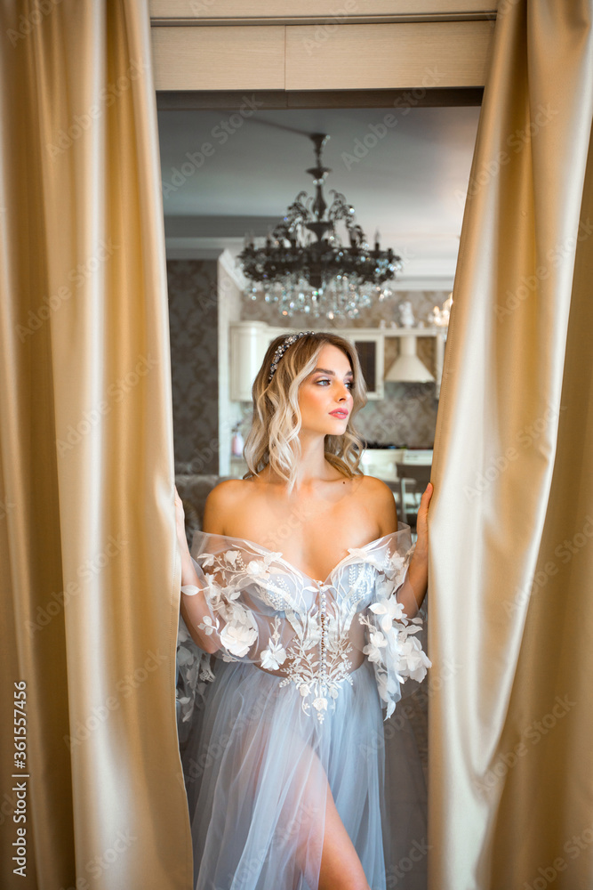 Fototapeta premium beautiful young woman in a delicate dress with makeup and hairstyle at home in the interior