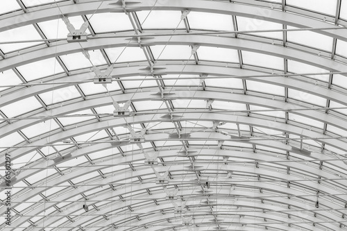 The transparent roof of a large shopping center in the form of an arch with lamps. Black and white photographs of buildings.