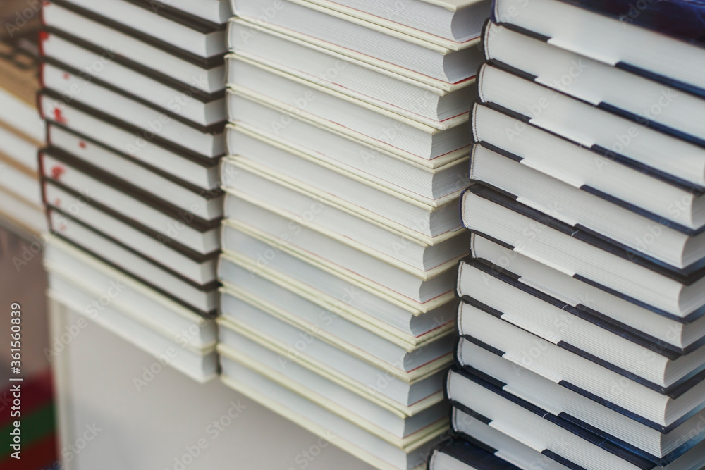 Many identical books are stacked on top of each other in a glass display case of a bookstore. Many identical books are stacked on top of each other in a glass display case of a bookstore.