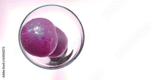  two plums in a glass cup on a white background      