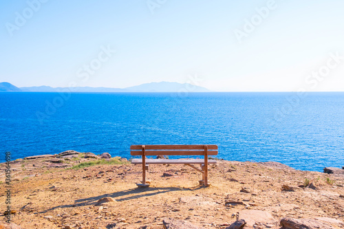 Empty bench against Tirrenian sea in Baratti, Tuscany, Italy. Cliff Buca delle Fate. Concept of hope or meditation in calm place