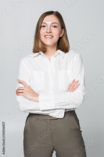Smiling business woman with folded hands against white background.
