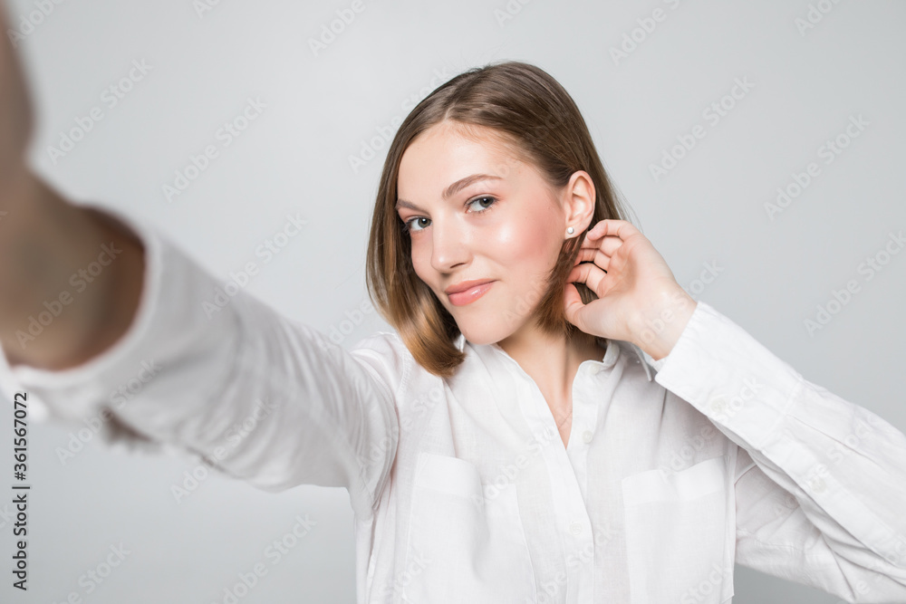 Portrait of smiling attractive woman taking a selfie while isolated over white background Portrait of smiling attractive woman taking a selfie while isolated over white background