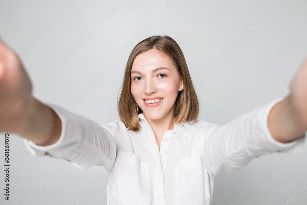 Portrait of smiling attractive woman taking a selfie while isolated over white background Portrait of smiling attractive woman taking a selfie while isolated over white background