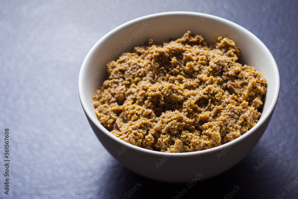 Ground olive spread in bowl on dark grey surface Ground olive spread in bowl on dark grey surface