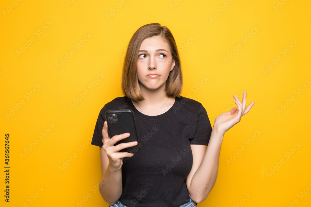 Portrait of smiling business woman using phone holding smartphone and looking back over yellow background. Portrait of smiling business woman using phone holding smartphone and looking back over yellow background.