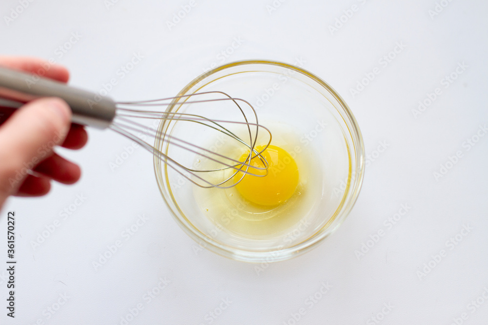 Woman Whipping eggs in glass bowl with whisk Woman Whipping eggs in glass bowl with whisk