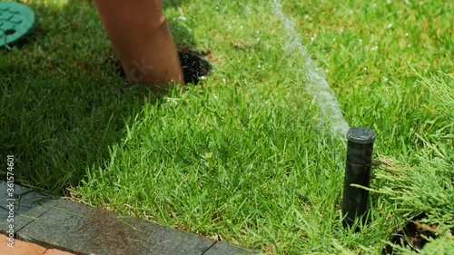Close-up turn-off watering the garden, grass and flowers in the Park, water drops in the sunlight. Automatic watering system for the grass and flowers. Drops of water are splashed in the sunlight. 