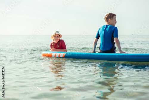 Two happy siblings teen children in neoprene suits having fun  with sup board in Baltic sea © spass