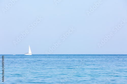 lonely white sail in front of cloudless sky. © Mikhail Pankov
