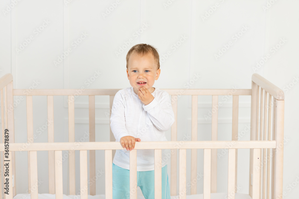 a small boy 2 years old is crying in the crib, parents do not approach the crying baby a small boy 2 years old is crying in the crib, parents do not approach the crying baby