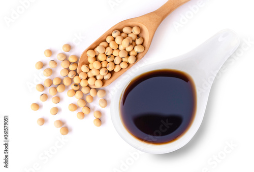 Billede på lærred Tasty soy sauce in white ceramic bowl with soy beans in wooden scoop  isolated on white background