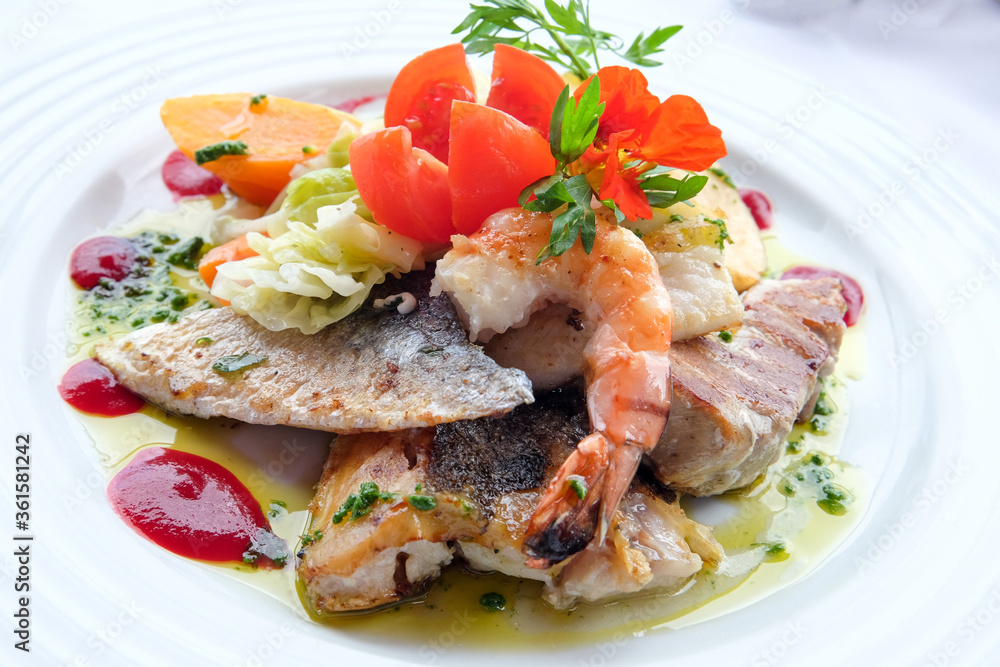 Delicious fish dish from traditional cuisine of Madeira island - grilled fillets of ocean codfish served with shrimps, shells, mussels and celery puree Delicious fish dish from traditional cuisine of Madeira island - grilled fillets of ocean codfish served with shrimps, shells, mussels and celery puree