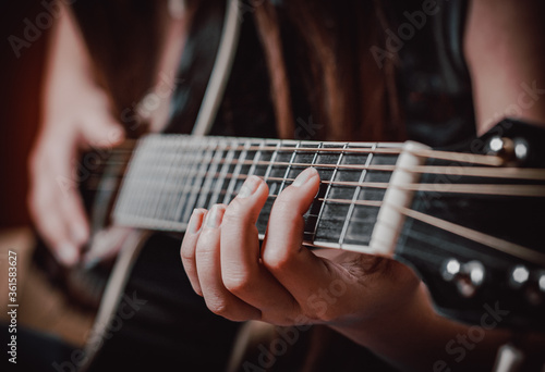 Closeup of young woman hand playing on black acoustic guitar