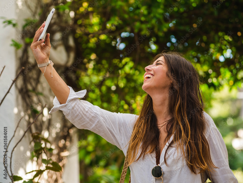A young caucasian female smiling and using her phone while walking in the street A young caucasian female smiling and using her phone while walking in the street
