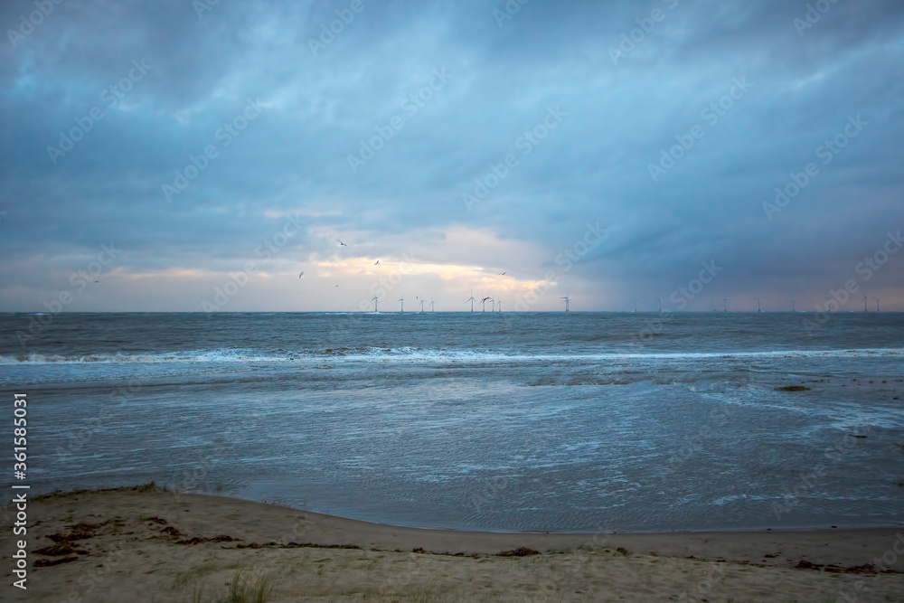 Distant offshore windfarm on the horizon. Coastal landscape scene. Clean energy background image.