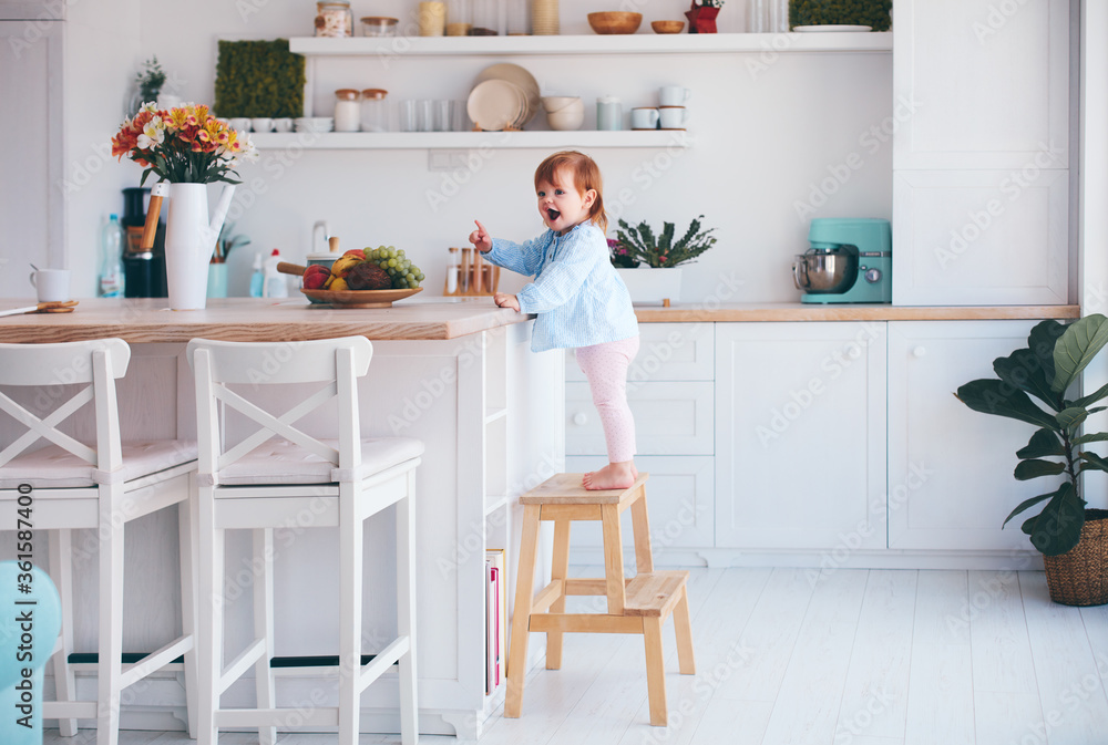 funny infant baby girl standing on a step stool at the cozy