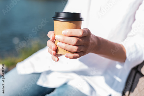 Woman drinking coffee from paper cup outdoors.