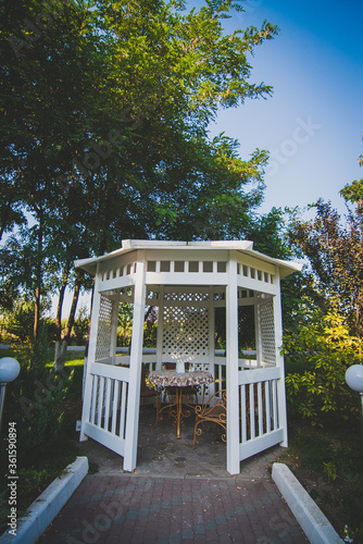 White wooden arbor on the street in a green park. A cozy place to spend time