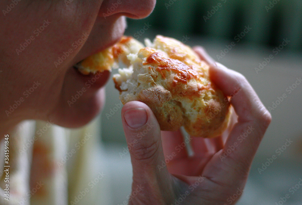 A woman eating cheese bread for breakfast, close up