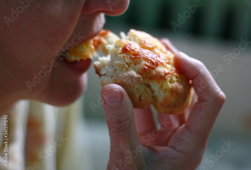 A woman eating cheese bread for breakfast, close up