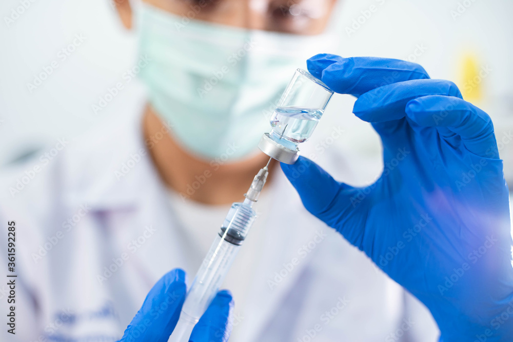 Doctor in blue glove filling syringe with vaccine Doctor in blue glove filling syringe with vaccine