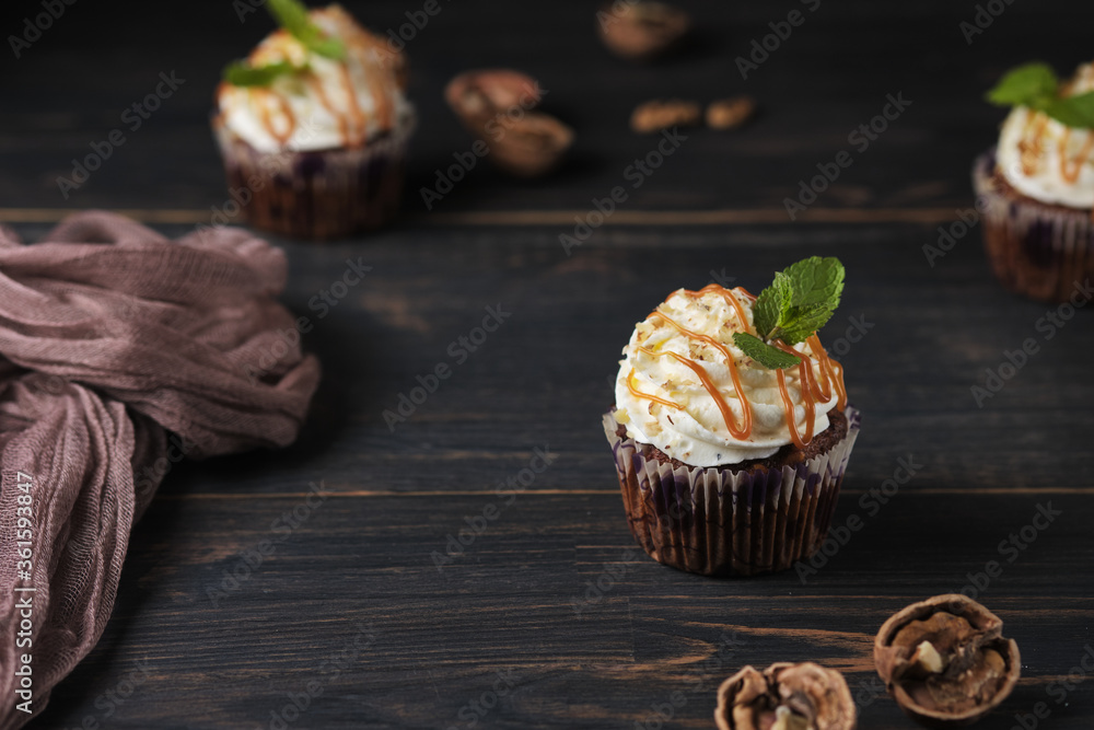 Carrot cupcakes stuffed with caramel and walnuts. Cupcakes with cream cheese cream and icing sugar. The dessert is decorated with mint and caramel. Carrot cupcakes stuffed with caramel and walnuts. Cupcakes with cream cheese cream and icing sugar. The dessert is decorated with mint and caramel.
