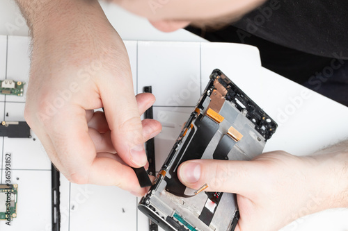 Parsing a mobile phone. A specialist repairs a smartphone in a service center