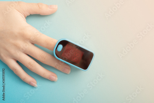Assessment of the function of the respiratory system. Female finger in a pulse oximeter on a blue background