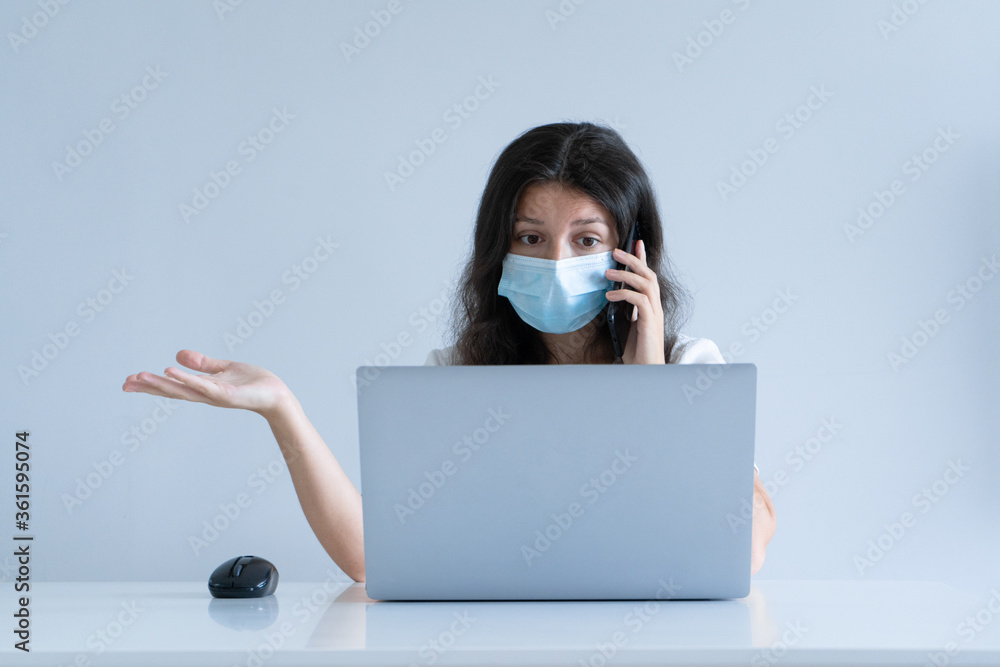 The girl works from home during quarantine. Corona virus pandemic. A girl in a surgical mask works on a laptop and drinks coffee. Distant work The girl works from home during quarantine. Corona virus pandemic. A girl in a surgical mask works on a laptop and drinks coffee. Distant work