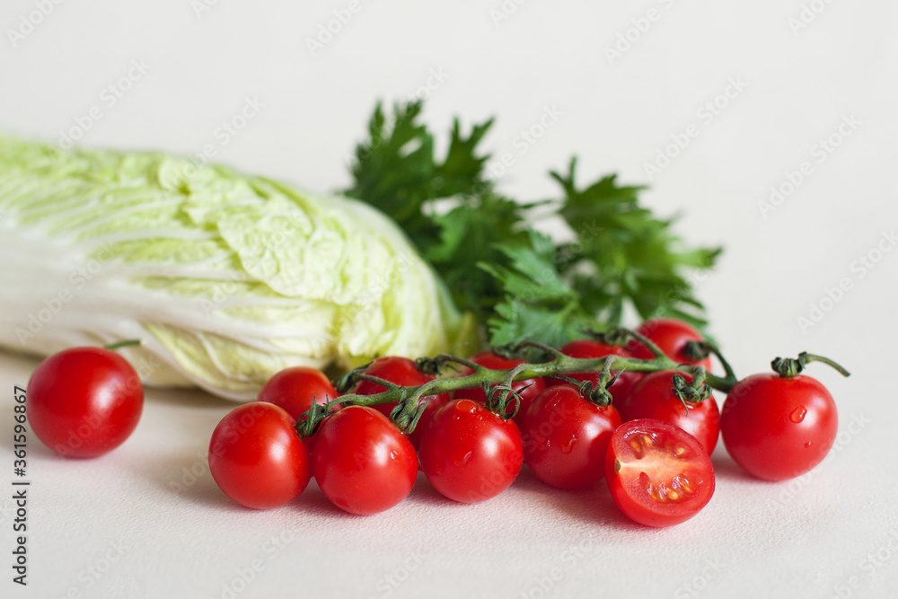 Vegetables cherry tomatoes with a twig, Peking cabbage and greens on a light background Vegetables cherry tomatoes with a twig, Peking cabbage and greens on a light background