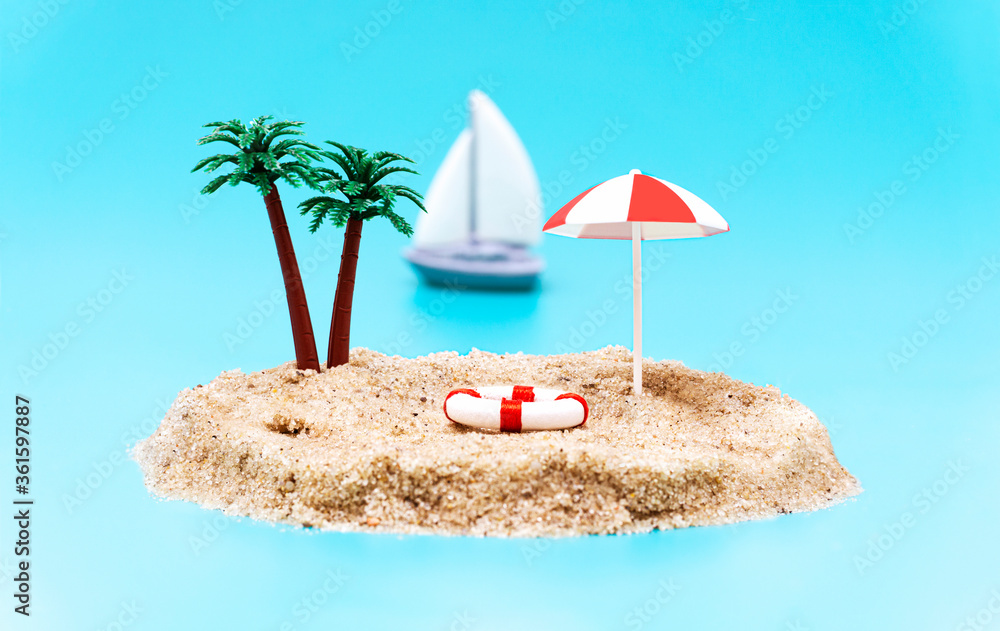 Miniature toy island with palm trees, sun umbrella, a lifebuoy and a