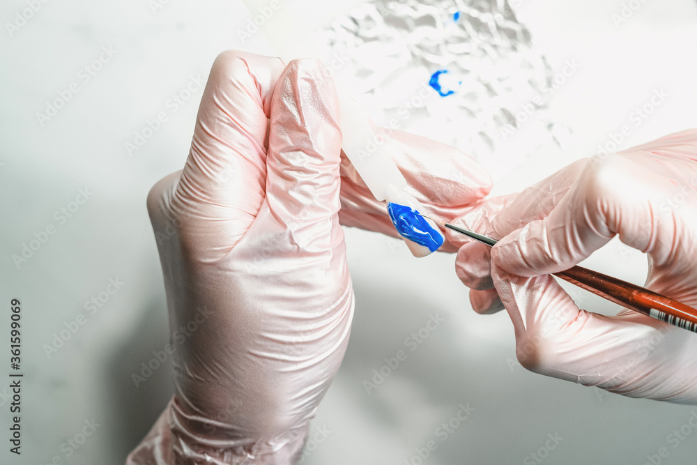 Manicurist at work in the office. Drawing gel polish on tips, creating a picture. Equipment and inventory of a manicure cabinet. Manicurist at work in the office. Drawing gel polish on tips, creating a picture. Equipment and inventory of a manicure cabinet.