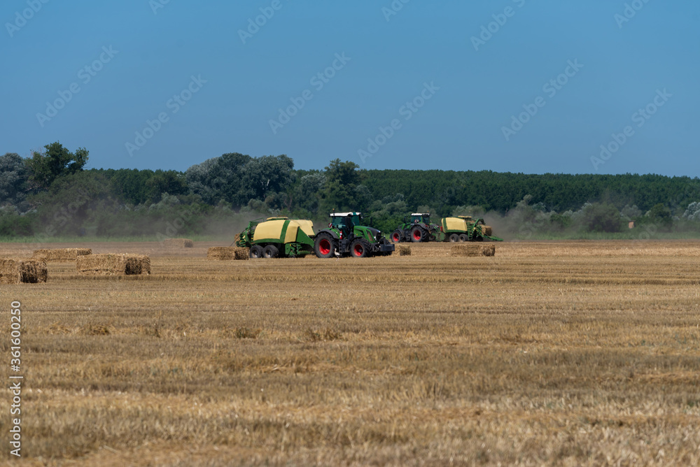 heavy machinery in the field performs agricultural work during the summer heavy machinery in the field performs agricultural work during the summer