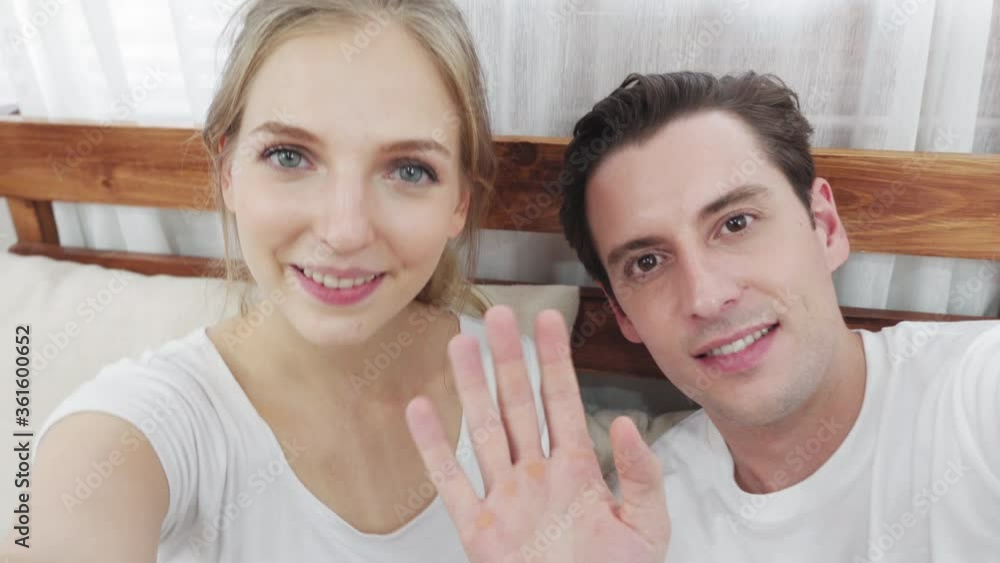 Caucasian smiling couple video conference at home. young man waving hand to greeting. social distancing, quarantine for Coronavirus prevention Caucasian smiling couple video conference at home. young man waving hand to greeting. social distancing, quarantine for Coronavirus prevention
